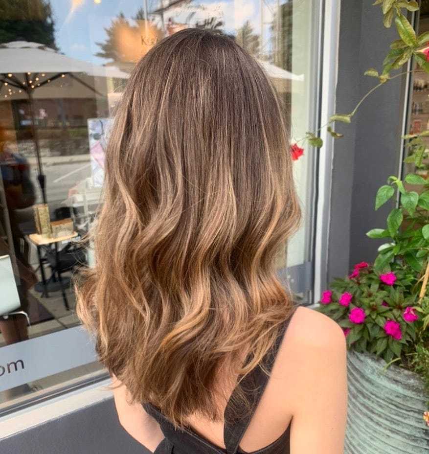 Wavy light brown hair in a salon setting, viewed from the back.