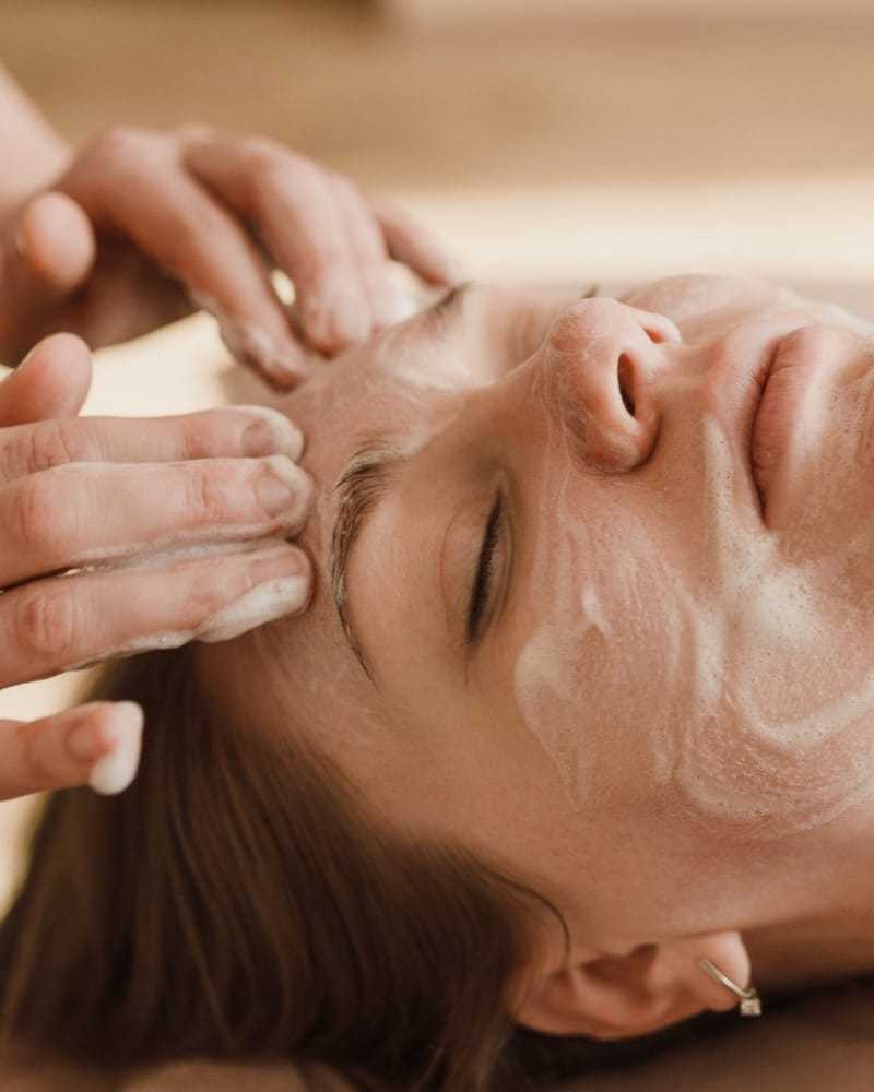 Facial massage with foam cleanser applied to a woman's face.