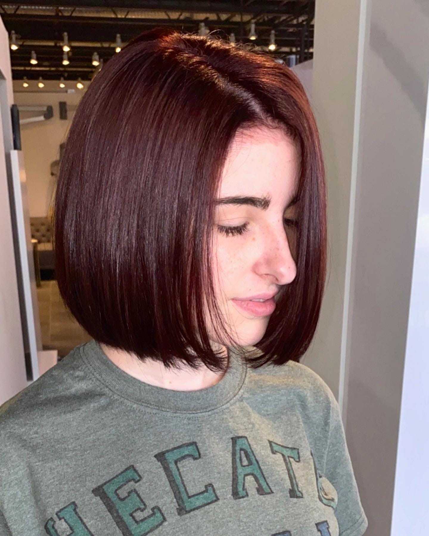 Woman with sleek auburn bob haircut in modern salon.